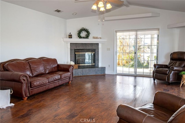 living room featuring a tiled fireplace, dark wood-type flooring, ceiling fan, and lofted ceiling with beams