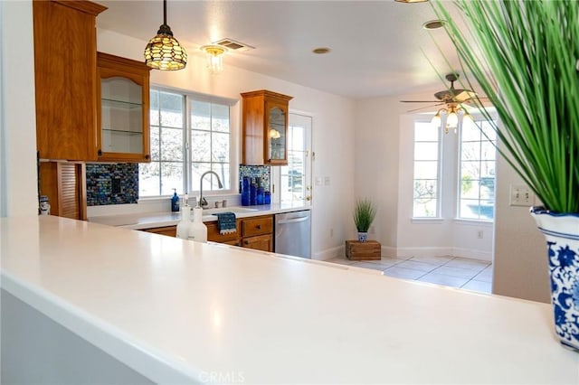 kitchen with sink, light tile patterned floors, dishwasher, decorative light fixtures, and kitchen peninsula