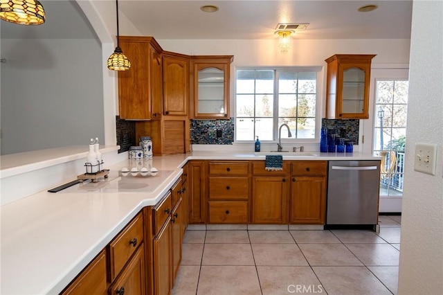 kitchen with sink, backsplash, hanging light fixtures, stainless steel dishwasher, and a healthy amount of sunlight