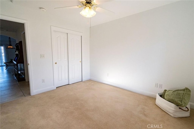 bedroom with light colored carpet, ceiling fan, and a closet