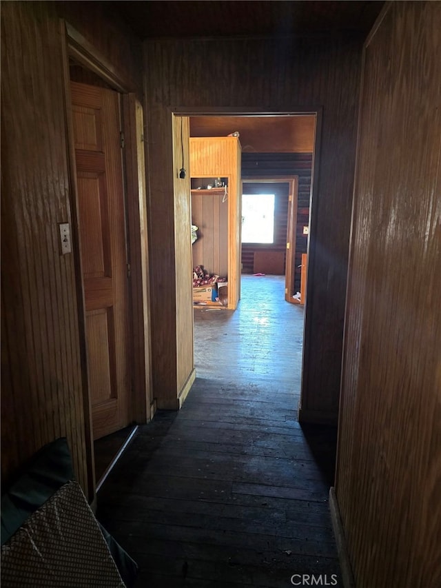 corridor with dark hardwood / wood-style flooring and wood walls