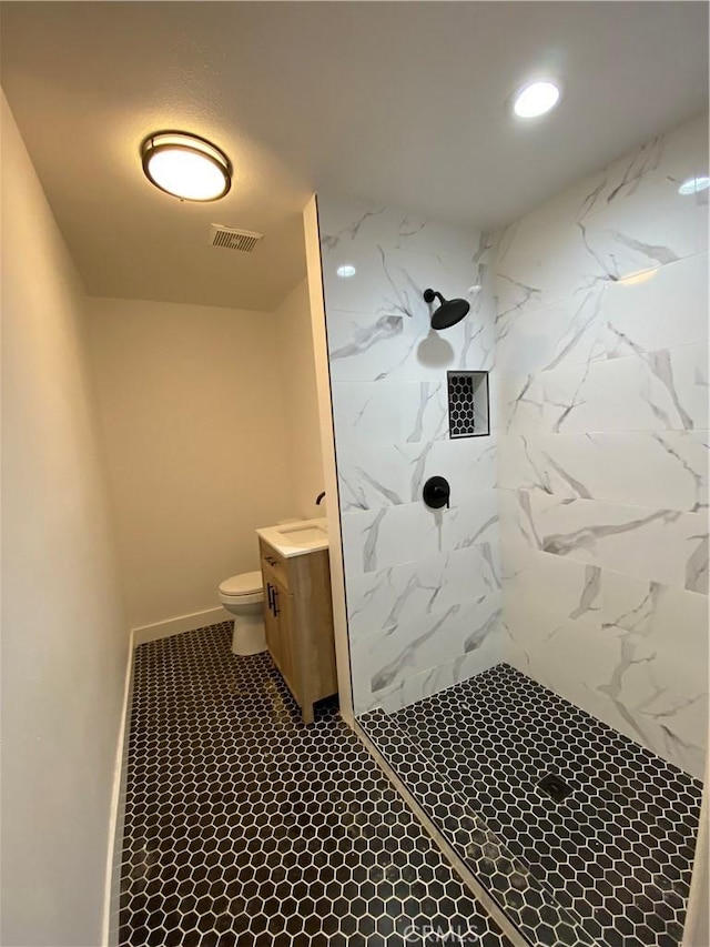 bathroom featuring tiled shower, vanity, and toilet