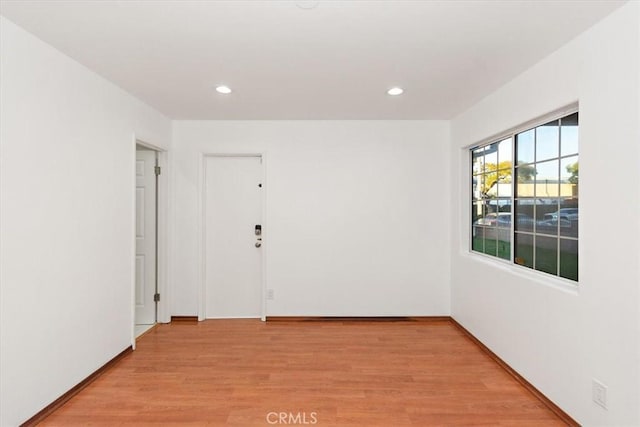 spare room featuring light wood-type flooring, baseboards, and recessed lighting