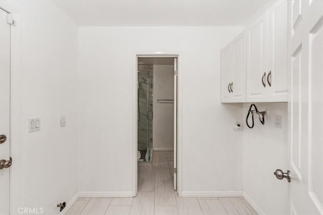 laundry room with cabinet space and baseboards