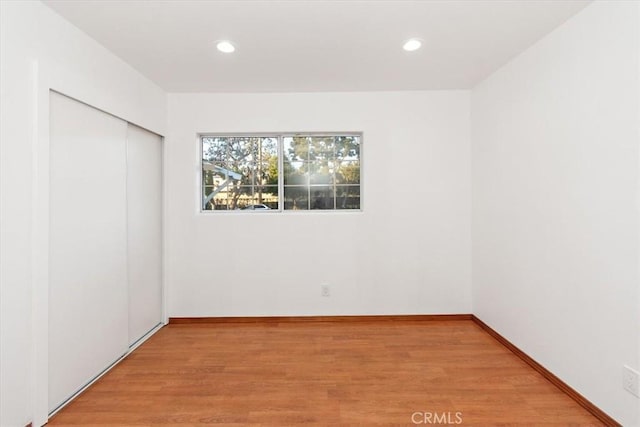 spare room featuring recessed lighting, light wood-style flooring, and baseboards