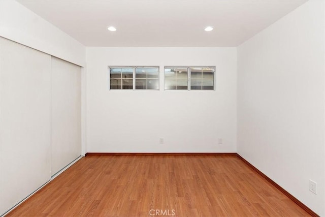 spare room featuring baseboards, wood finished floors, and recessed lighting