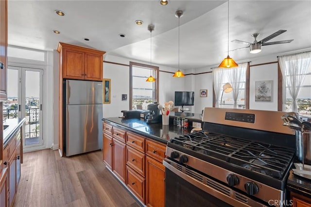 kitchen featuring ceiling fan, stainless steel appliances, hardwood / wood-style floors, and hanging light fixtures