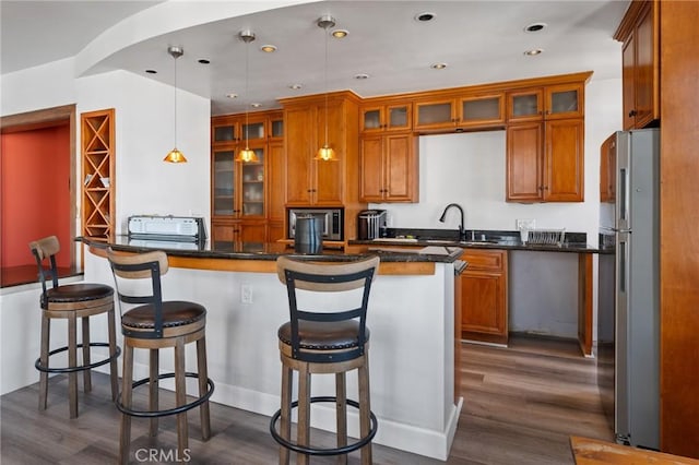 kitchen featuring a kitchen bar, sink, stainless steel refrigerator, dark hardwood / wood-style flooring, and pendant lighting