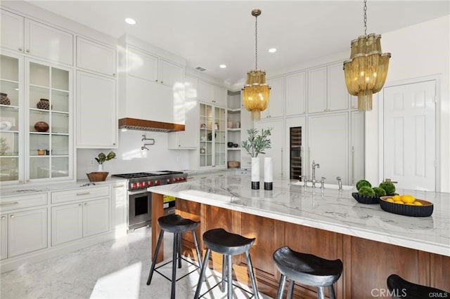 kitchen featuring a kitchen breakfast bar, white cabinetry, light stone countertops, and high end range