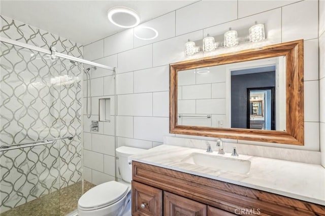 bathroom with vanity, toilet, an enclosed shower, and tile walls