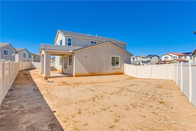 back of house featuring a patio area, a residential view, stucco siding, and a fenced backyard