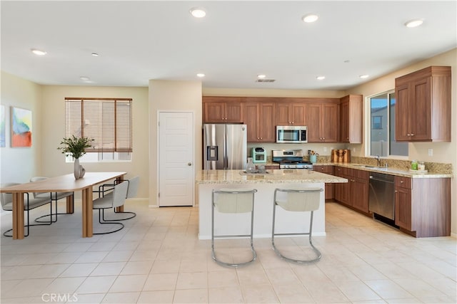 kitchen featuring light stone countertops, recessed lighting, appliances with stainless steel finishes, and a center island