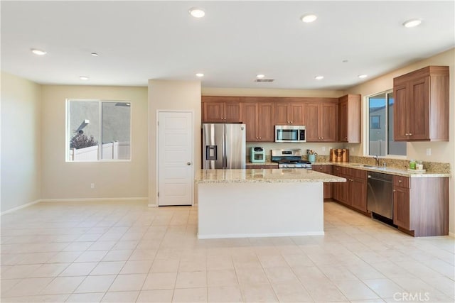 kitchen with a kitchen island, recessed lighting, stainless steel appliances, and light stone countertops