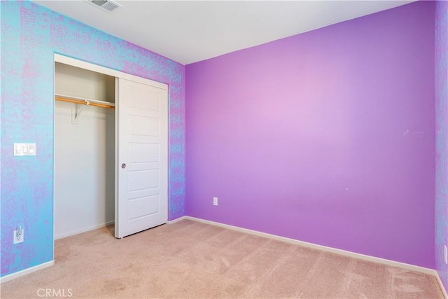 unfurnished bedroom with light colored carpet, visible vents, a closet, and baseboards