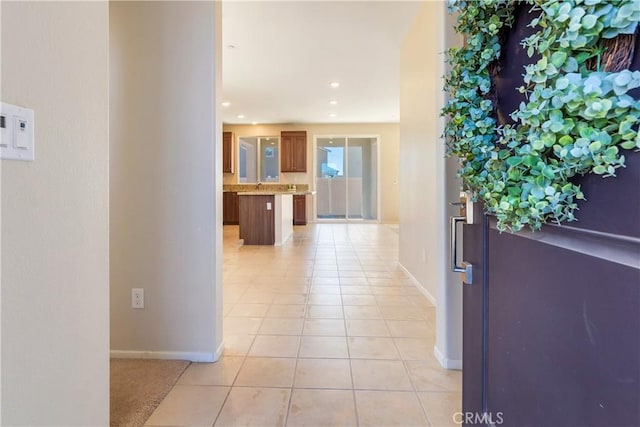 hall with light tile patterned floors, baseboards, recessed lighting, and a sink