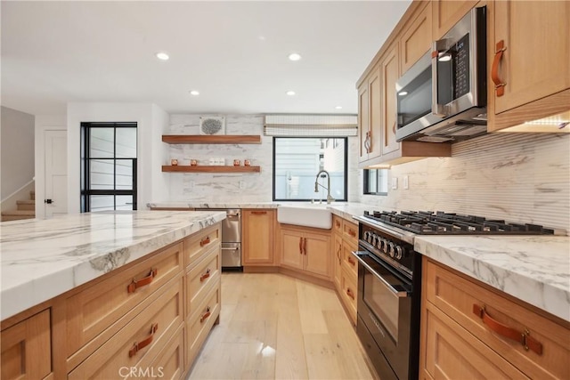 kitchen with light stone counters, sink, backsplash, and black gas stove