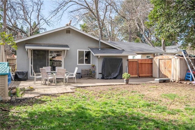 back of property with a storage unit, a yard, and a patio area