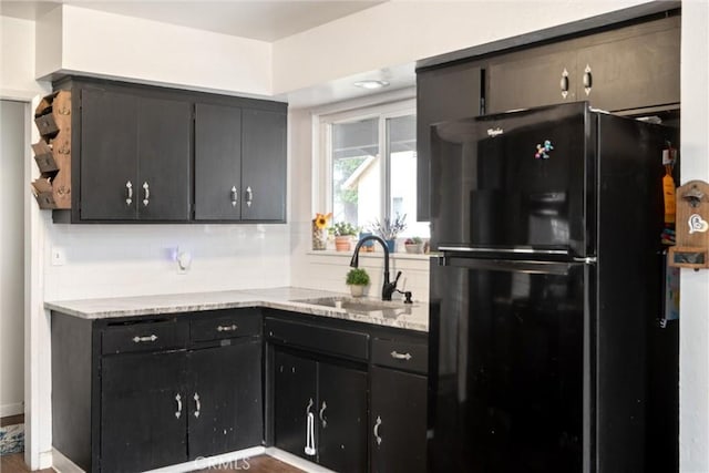 kitchen with black refrigerator, sink, and tasteful backsplash