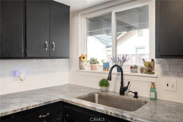 kitchen with sink, light stone counters, and decorative backsplash