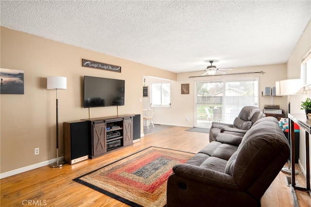 living room featuring ceiling fan, a textured ceiling, and light wood-type flooring