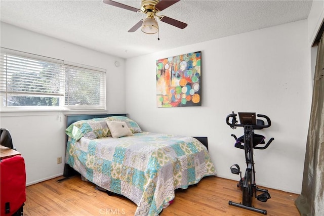 bedroom with ceiling fan, hardwood / wood-style flooring, and a textured ceiling