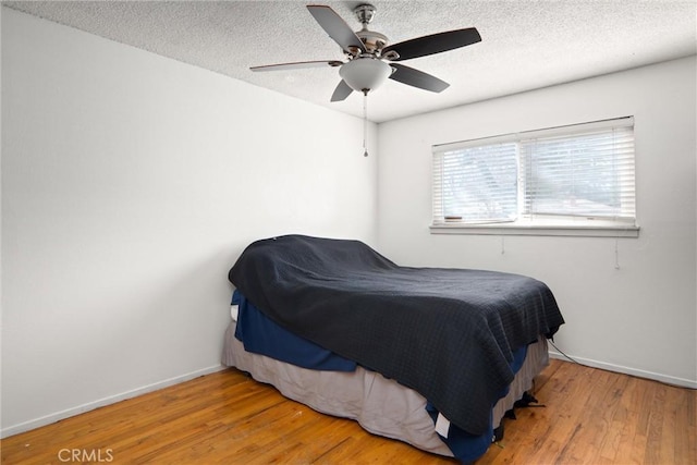 bedroom featuring hardwood / wood-style floors, a textured ceiling, and ceiling fan