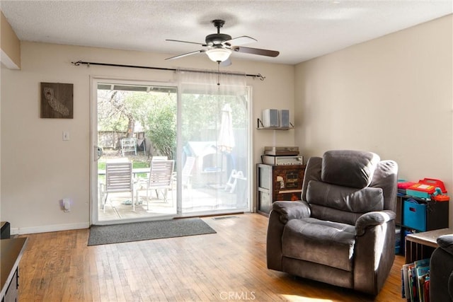 living area featuring hardwood / wood-style floors, a textured ceiling, and ceiling fan