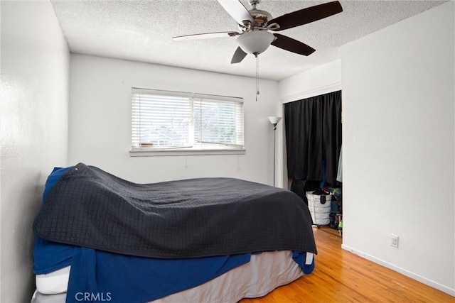 bedroom with ceiling fan, hardwood / wood-style flooring, and a textured ceiling