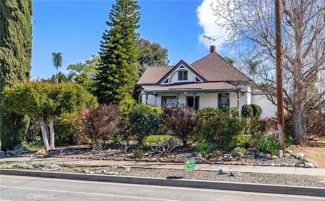 victorian-style house with a shingled roof and stucco siding