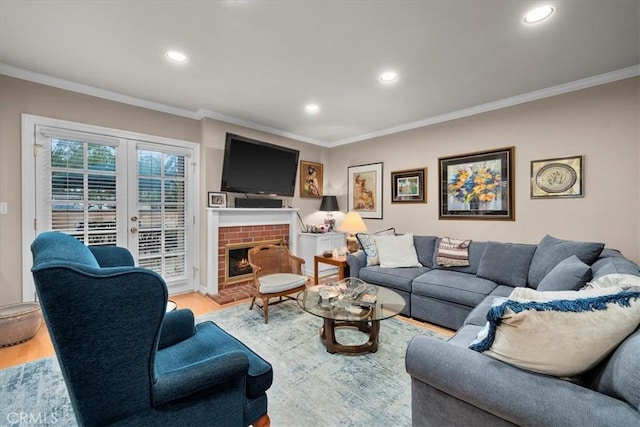 living room with ornamental molding, light wood-type flooring, french doors, and a brick fireplace