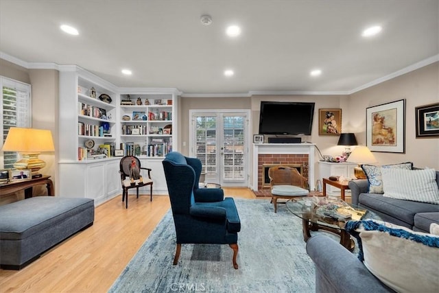 living room featuring crown molding, a fireplace, light hardwood / wood-style floors, and french doors