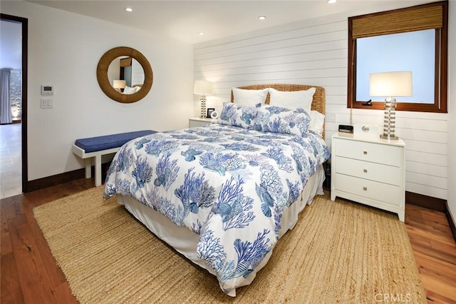 bedroom with light wood-type flooring and wooden walls