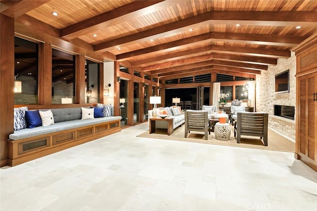 interior space featuring beam ceiling, an outdoor stone fireplace, and wooden ceiling