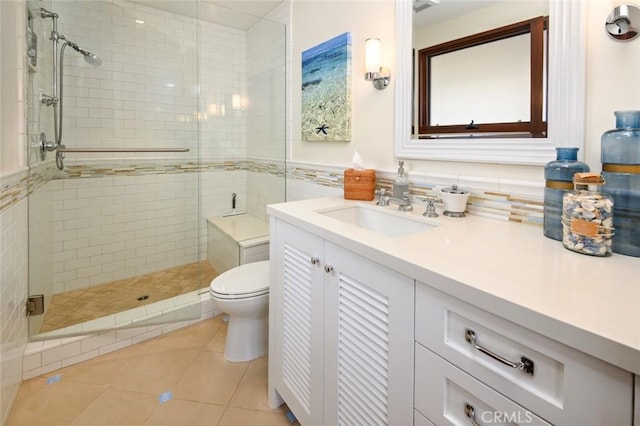 bathroom featuring tile patterned floors, toilet, vanity, and a shower with shower door