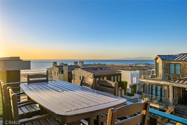 balcony at dusk featuring a water view