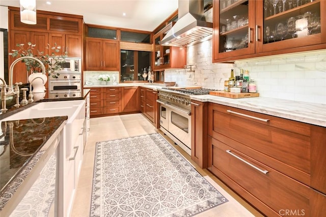 kitchen with decorative backsplash, ventilation hood, stainless steel appliances, and light stone counters