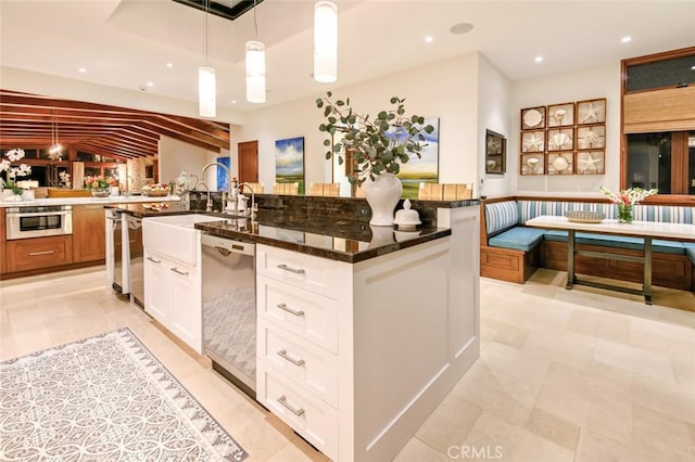 kitchen featuring white cabinetry, dark stone counters, breakfast area, decorative light fixtures, and stainless steel appliances