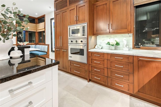 kitchen featuring dark stone counters, backsplash, white cabinetry, and stainless steel appliances