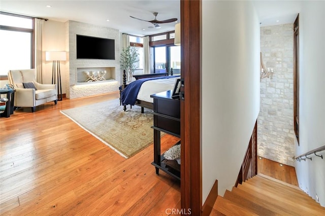 bedroom featuring a multi sided fireplace, light hardwood / wood-style flooring, and ensuite bath