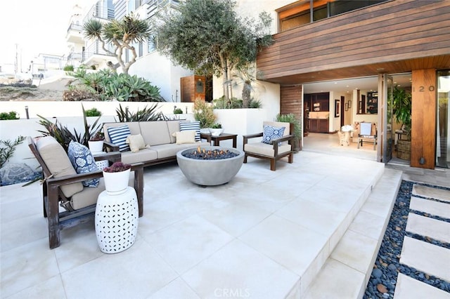 view of patio with an outdoor living space with a fire pit