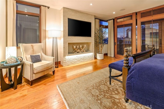 bedroom featuring wood-type flooring, access to exterior, and a large fireplace