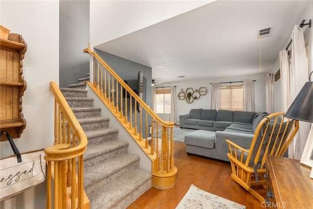 living area featuring a ceiling fan, stairs, visible vents, and wood finished floors