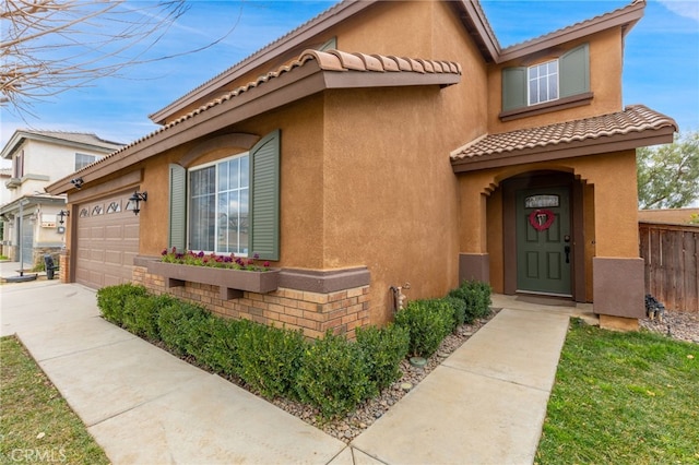 view of front facade featuring a tiled roof, fence, and stucco siding