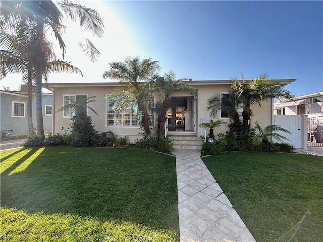 view of front of home with fence, a front lawn, and stucco siding