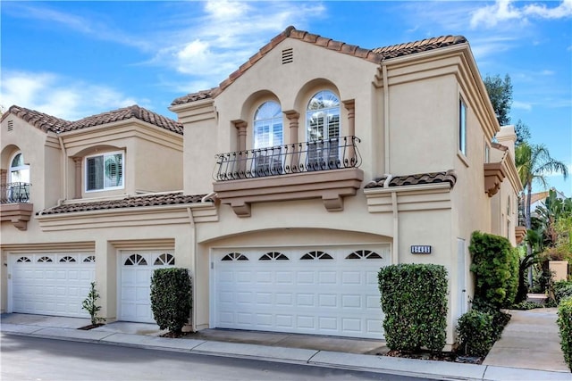 mediterranean / spanish-style house featuring a tiled roof, a balcony, a garage, and stucco siding