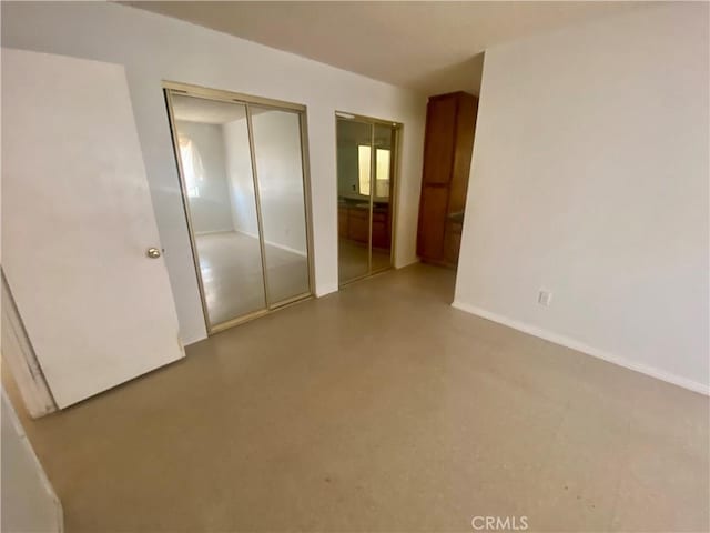 unfurnished bedroom with baseboards and two closets