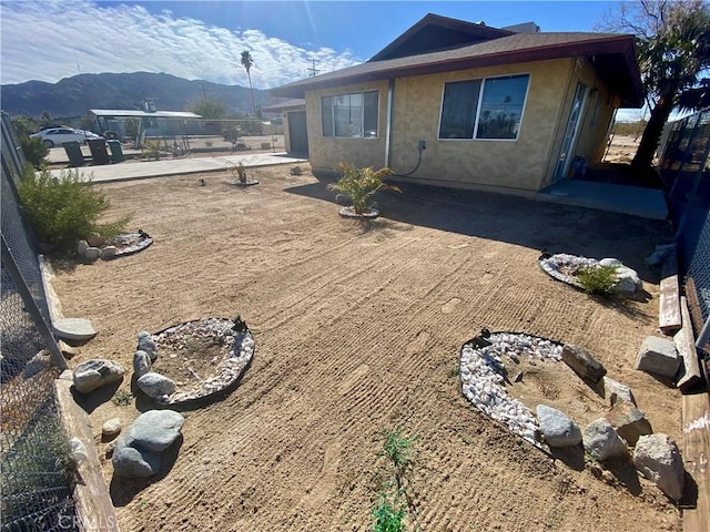 rear view of house with a patio, fence, a mountain view, and stucco siding