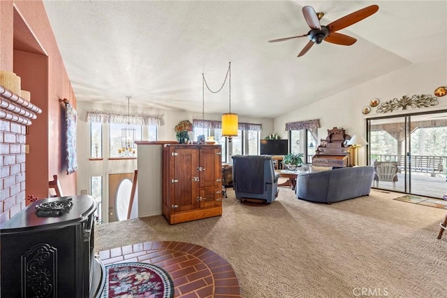 living room with vaulted ceiling, ceiling fan, carpet floors, and a wood stove