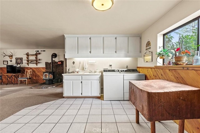 kitchen featuring separate washer and dryer, a wood stove, sink, white cabinets, and light carpet