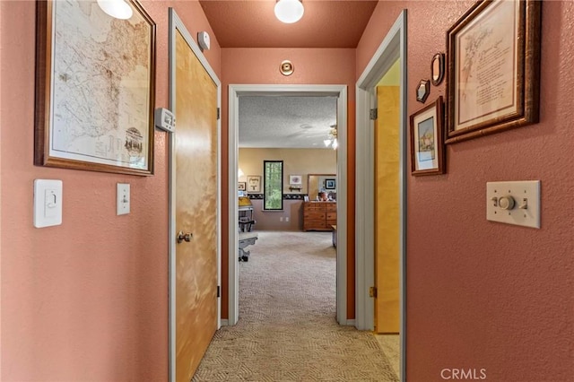 hall with light colored carpet and a textured ceiling